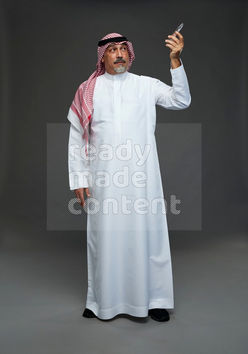 Saudi man with shomag Standing Interacting with the camera on gray background