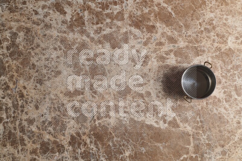 A small copper pot on beige marble background