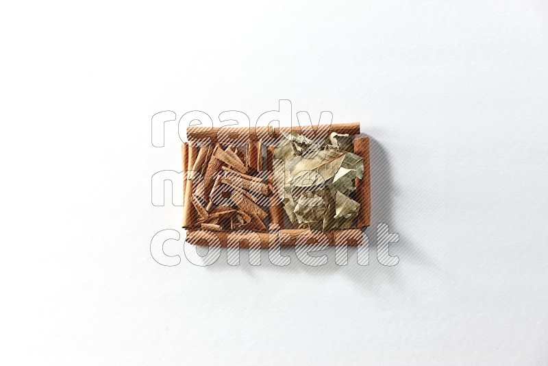 2 squares of cinnamon sticks full of cinnamon and bay laurel leaves on white flooring