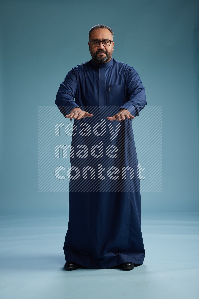 Saudi Man without shimag Standing Interacting with the camera on blue background