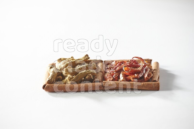 مربعان من أعواد القرفة ممتلئان بالفلفل الحار المجفف وأصابع الكركم علي خلفية بيضاء