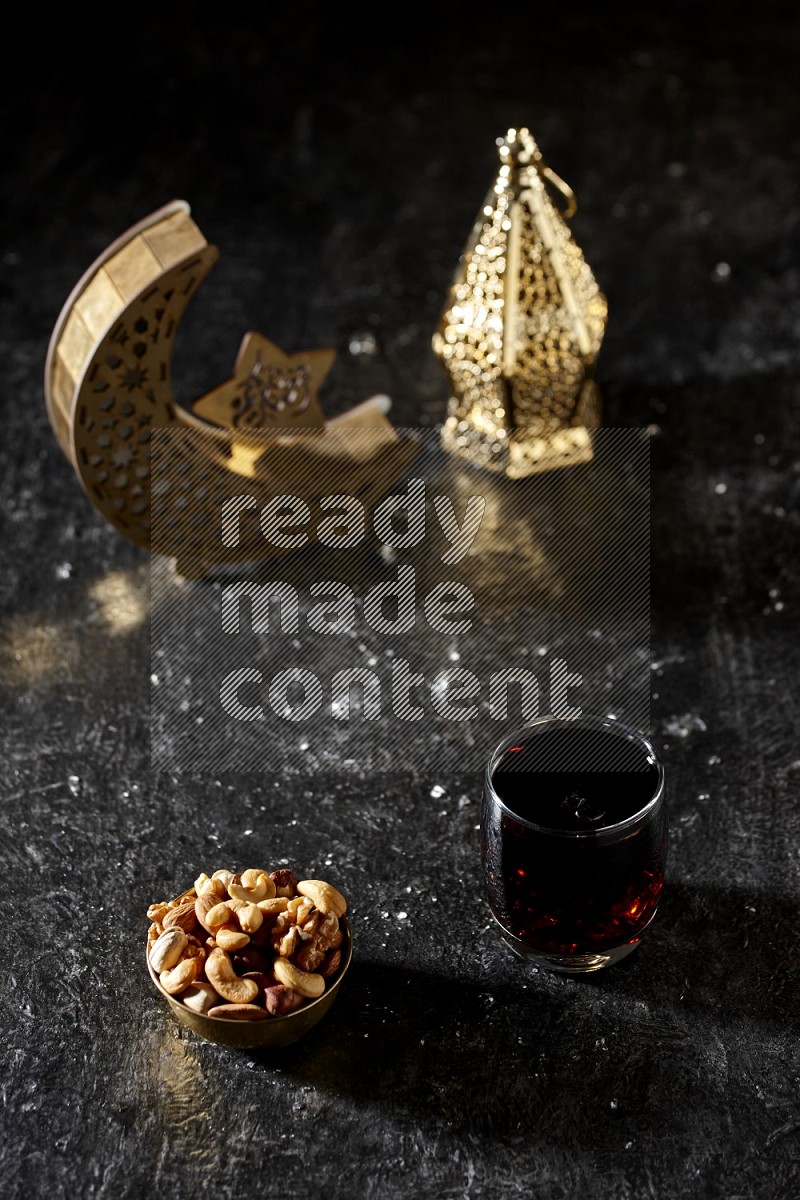 Nuts in a metal bowl with tamarind beside golden lanterns in a dark setup