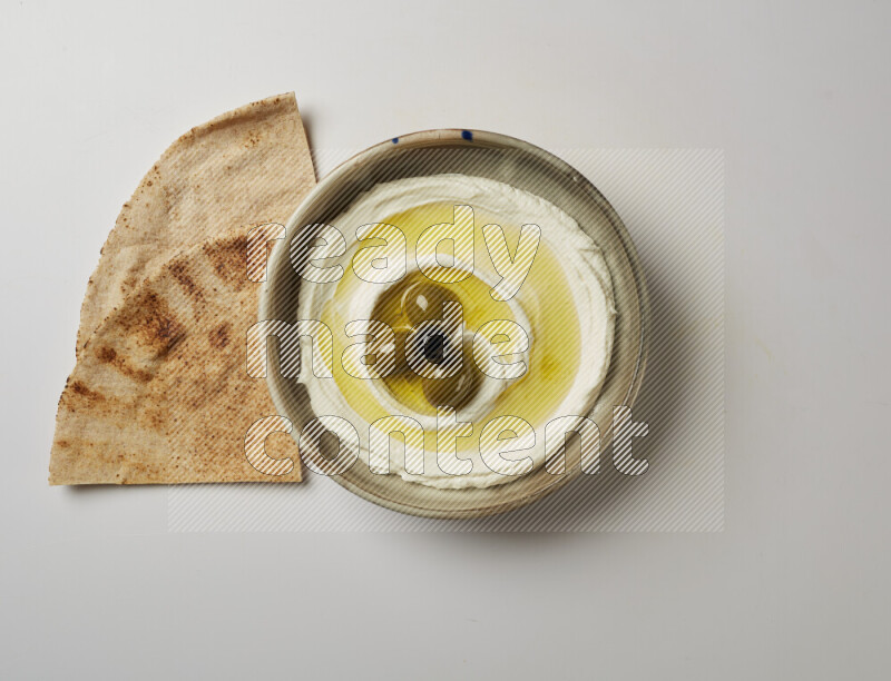 Lebnah garnished with whole olives in a grey pottery plate on a white background
