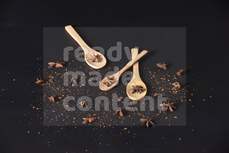 Star Anise in wooden spoons on black flooring