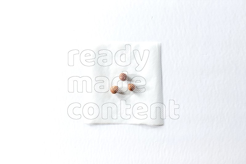 3 peeled hazelnuts on a piece of paper on a white background in different angles