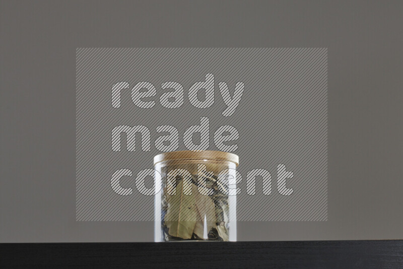 Bay laurel leaves in a glass jar on black background