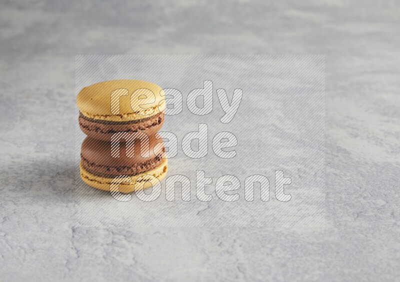 45º Shot of two Yellow and Brown Chai Latte macarons r on white  marble background