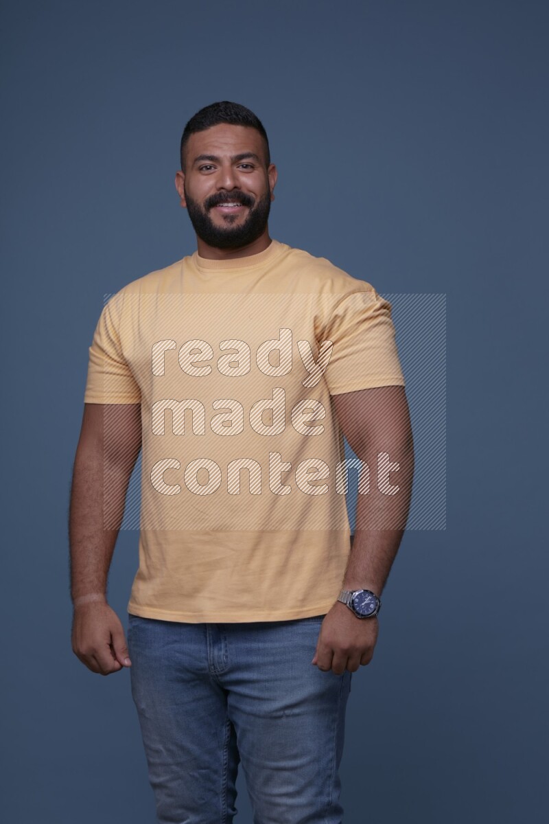 رجل يرتدي قميص اصفر بأكمام قصيرة وبنطال جينز ازرق يقف بأوضاع مختلفة