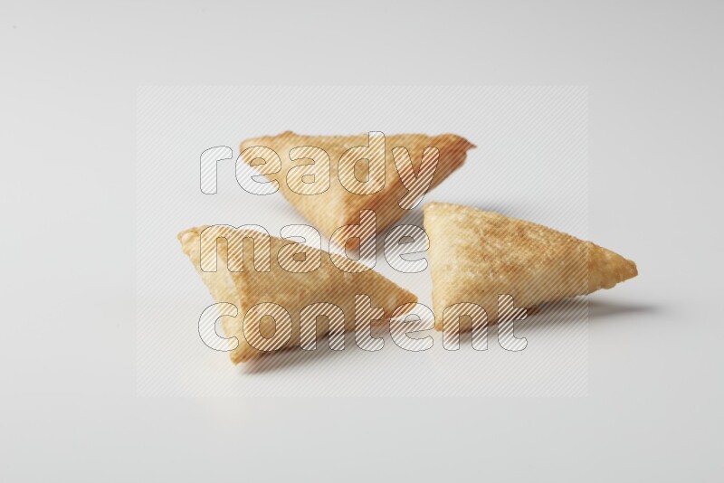 Three fried sambosas on a white background