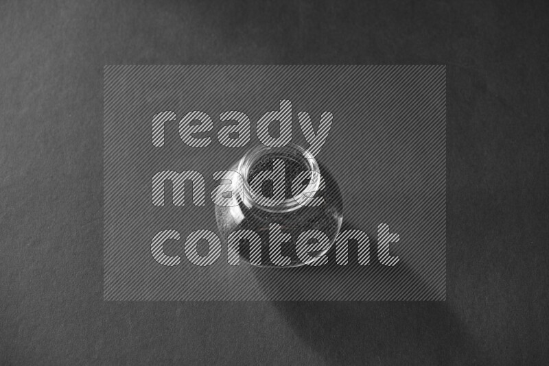 حبة البركة في وعاء زجاجي علي خلفية سوداء