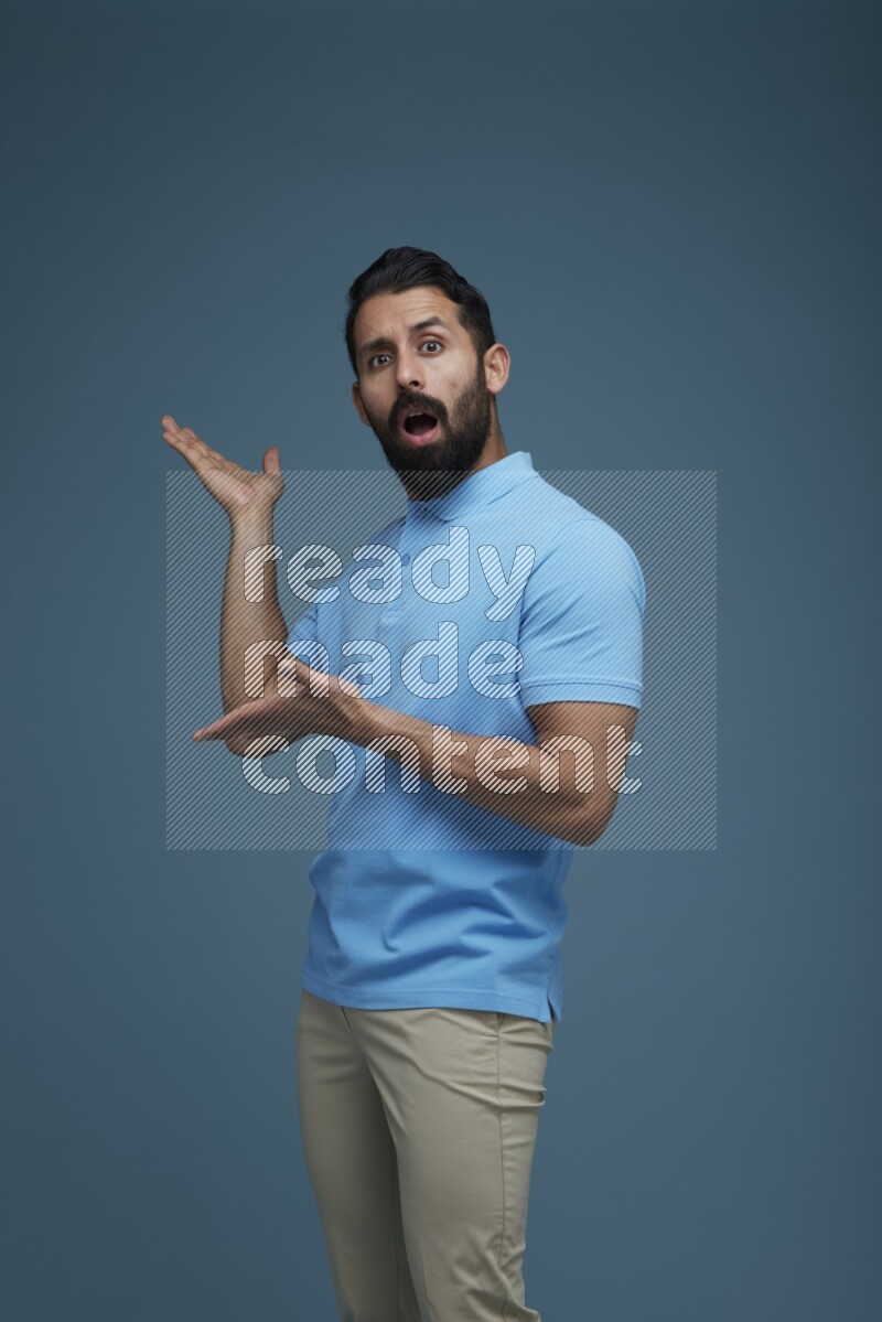 A man pointing  in a blue background wearing a Blue shirt