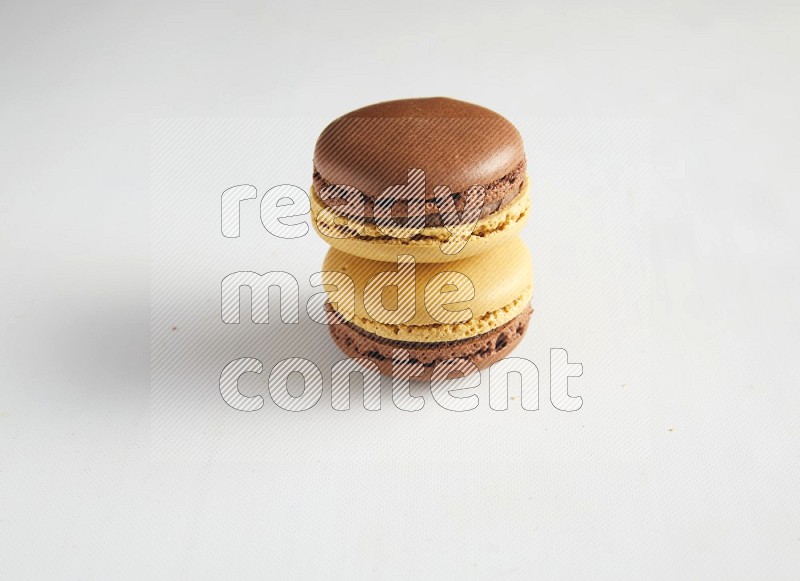 45º Shot of two Yellow and Brown Chai Latte macarons on white background