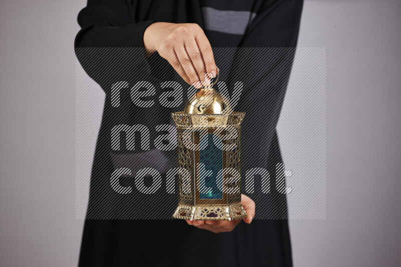 A woman in black abaya holding different ramadan lanterns in different positions