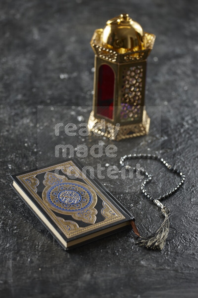A golden lantern with different drinks, dates, nuts, prayer beads and quran on textured black background