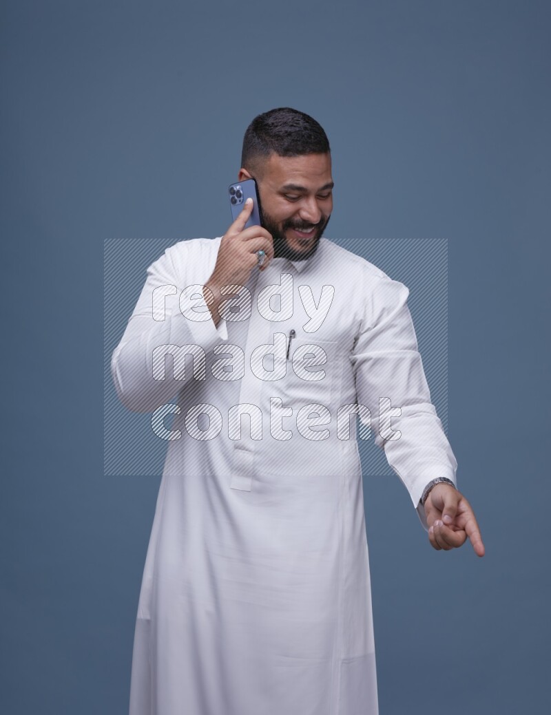 A Saudi man calling on blue background wearing Saudi Thob