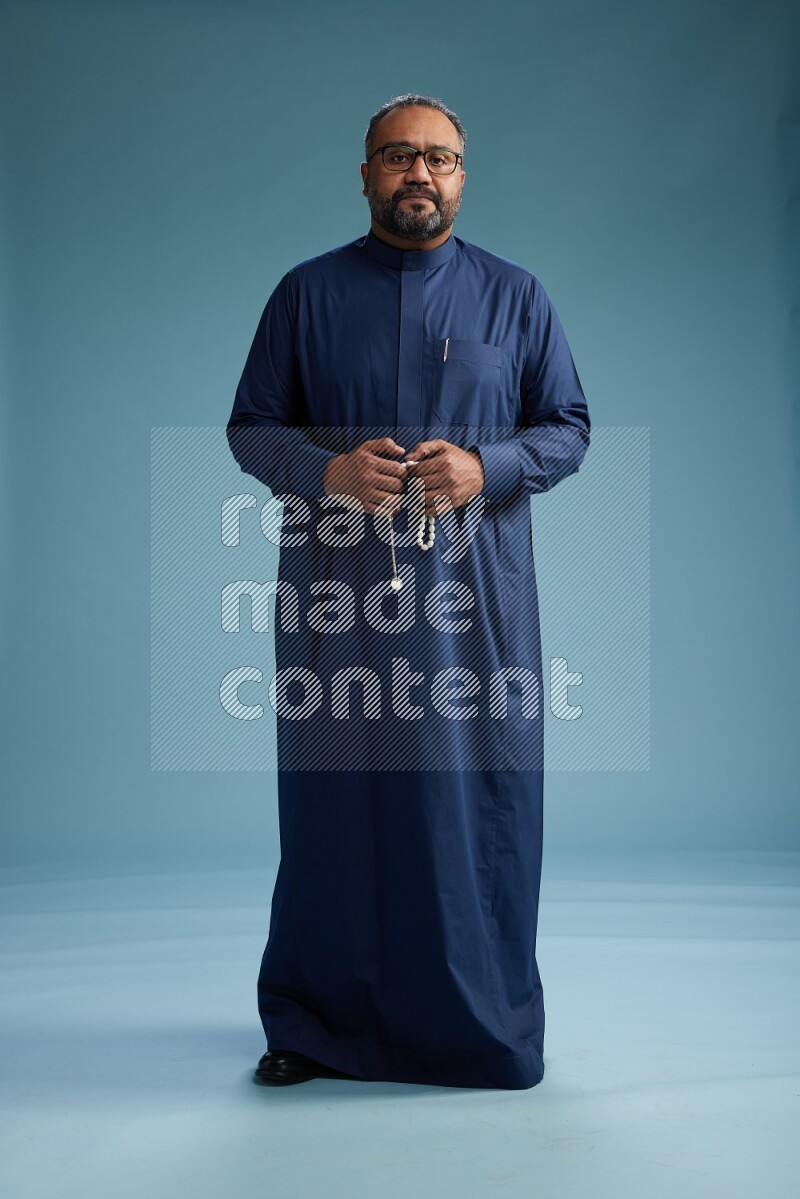 Saudi Man without shimag Standing Interacting with the camera on blue background