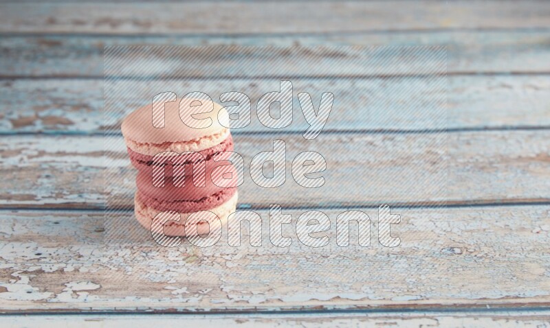 45º Shot of two Pink Litchi Raspberry macarons on light blue wooden background