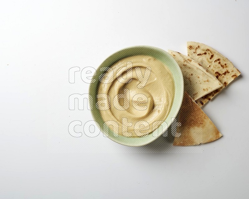 plain Hummus in a green plate on a white background