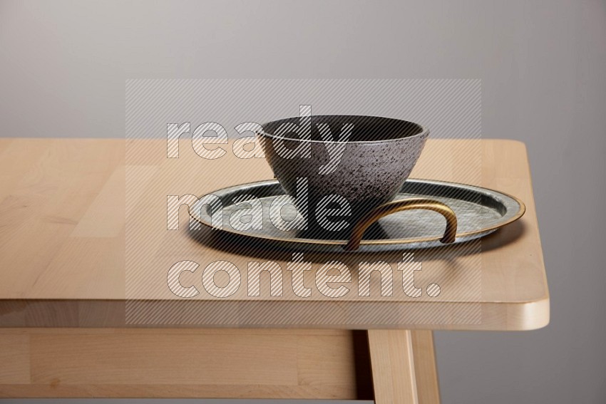 multicolored bowl placed on a rounded stainless steel tray with golden handels on the edge of wooden table