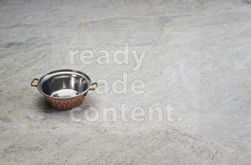 A Small Copper Pot On Grey Marble Flooring