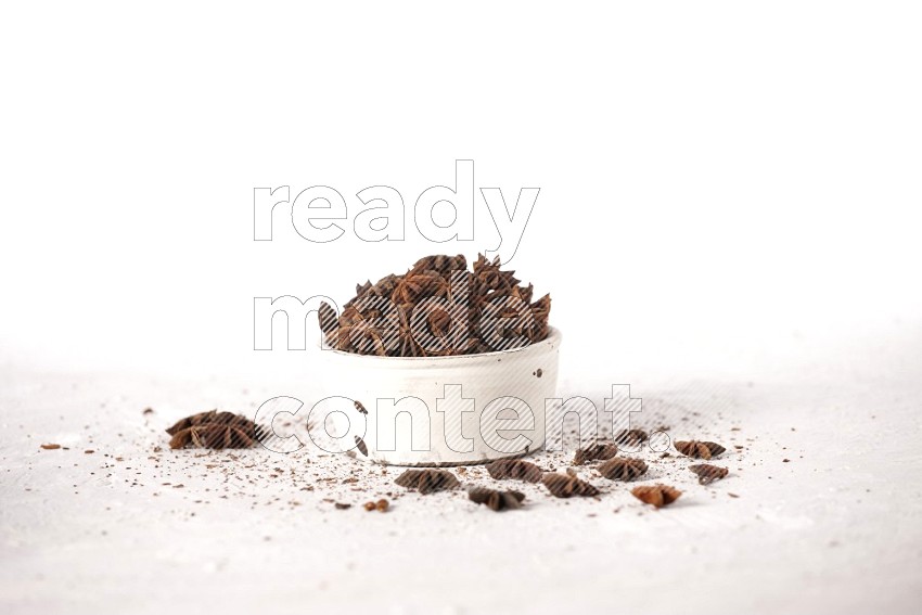 Star Anise in a white bowl and more herbs sprinkled on white background in different angles