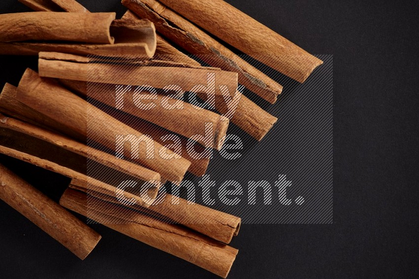 Cinnamon sticks stacked in different angles, black flooring