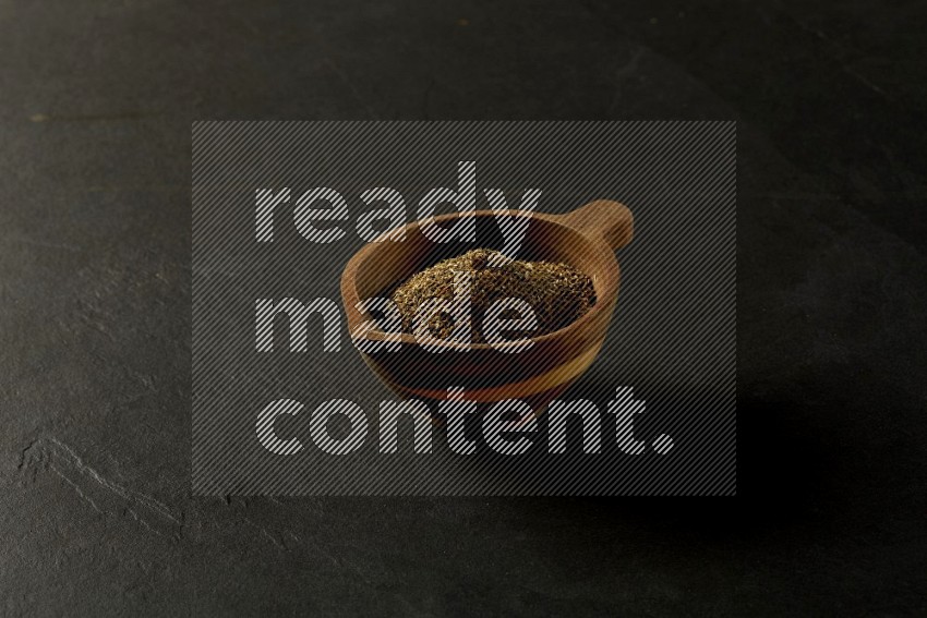 wooden round sauce bowl filled with herbs on grey textured countertop