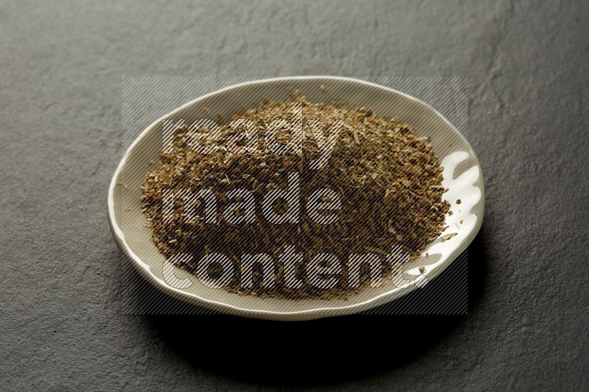 white ceramic round sauce dish filled with herbs on grey textured countertop