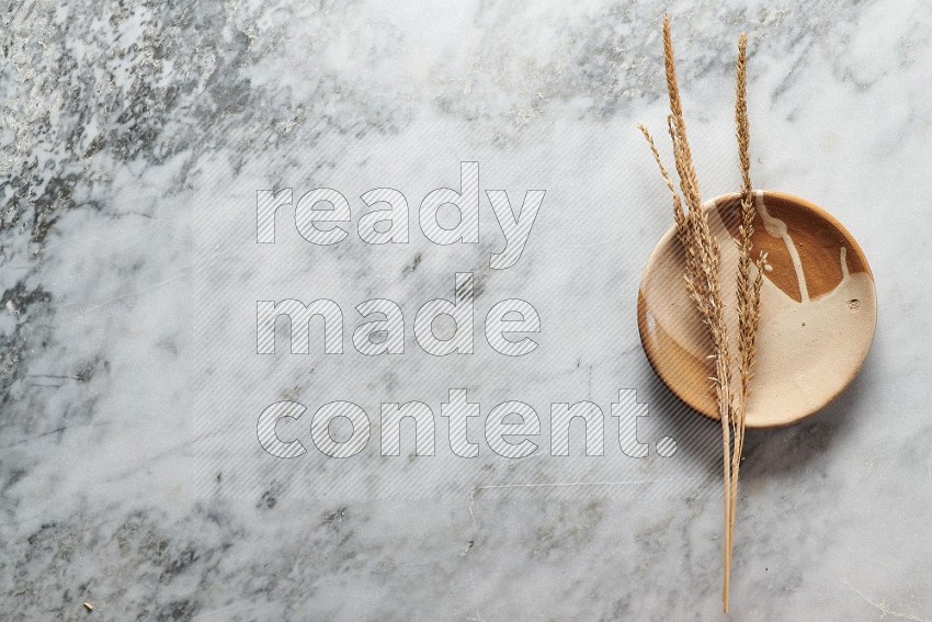 Wheat stalks on Multicolored Pottery Plate on grey marble flooring, Top view