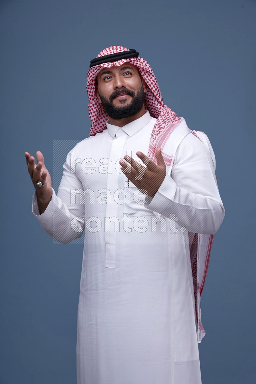 A man Taking A Posing on Blue Background wearing Saudi Thob with Shomag