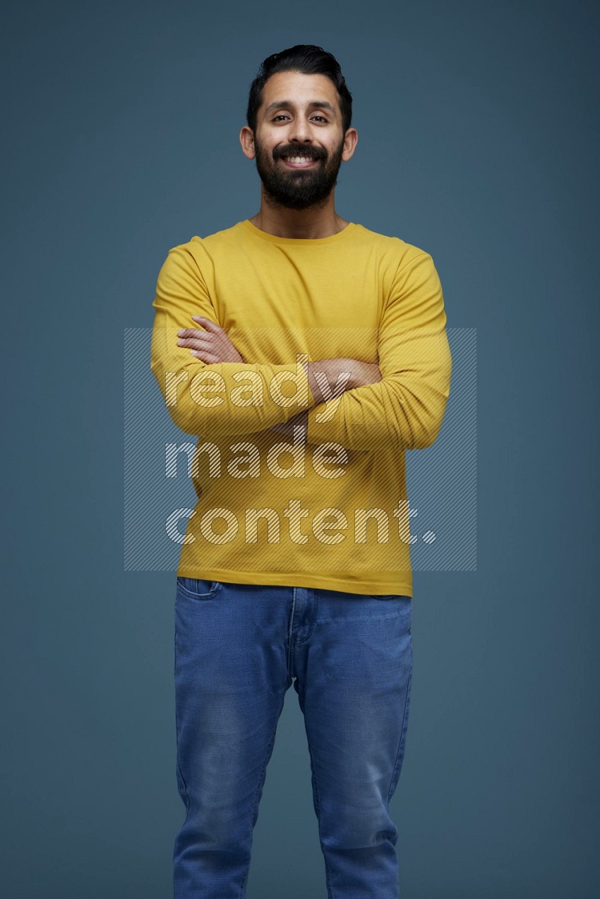 Man posing in a blue background wearing a yellow shirt