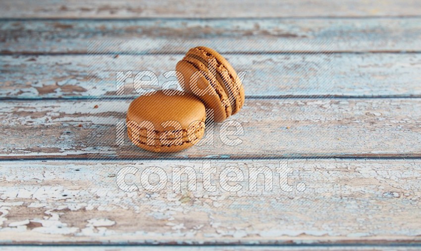 45º Shot of two Brown Maple Taffy macarons on light blue wooden background
