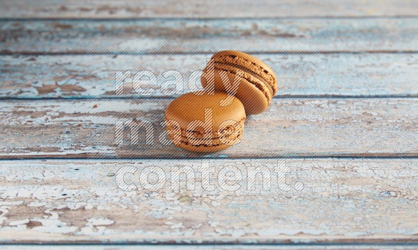45º Shot of two Brown Maple Taffy macarons on light blue wooden background