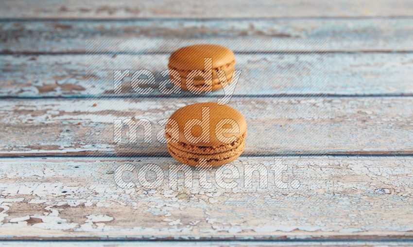 45º Shot of two Brown Maple Taffy macarons on light blue wooden background