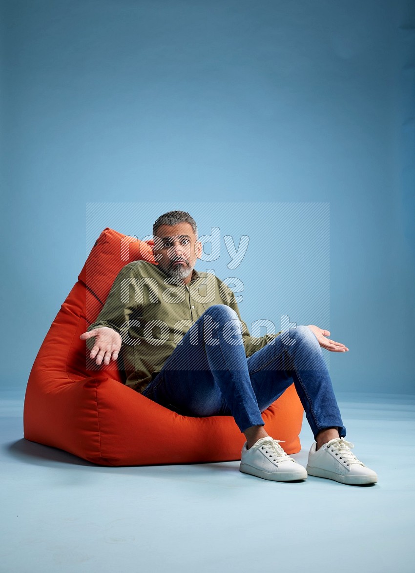 A man sitting on an orange beanbag and interacting with the camera