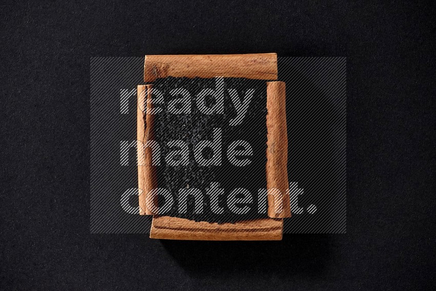A single square of cinnamon sticks full of black seeds on black flooring